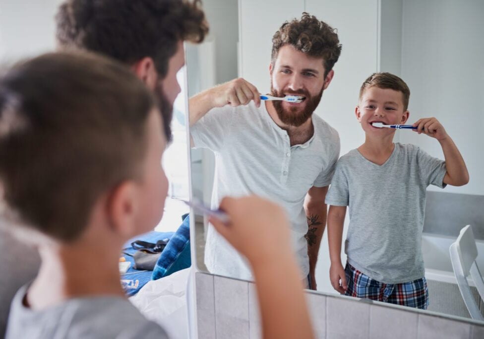 Shot of a father and his little son brushing their teeth together in the bathroom at home